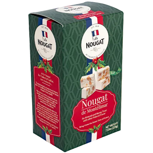 A boxed food product labeled Le Nougat de Monttlimar, shown at a slight angle on a plain light beige background. The package is dark green with red and white label panels, a French flag motif, and a photo of nougat bars on the front.