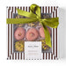 Gift box with a green ribbon containing pastries and pistachios, branded 'Peccatucci'.